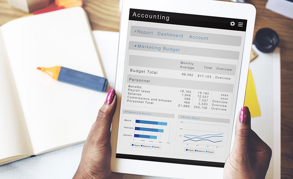 Person holding a tablet displaying an accounting dashboard with budget totals and personnel expenses; notebook, highlighter, and pen on the desk—perfect setup for exploring the Best Bookkeeping Courses Online.